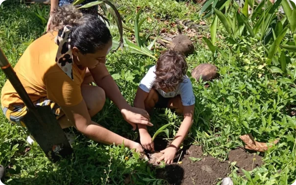 señora y niña sembrando arboles en la playa